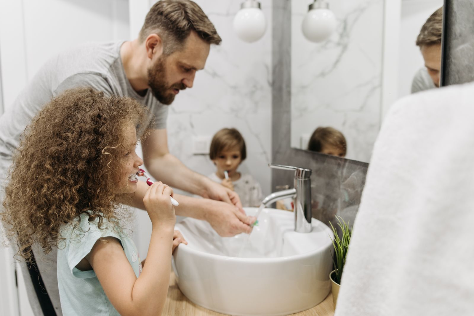 Father and children brushing their teeth together