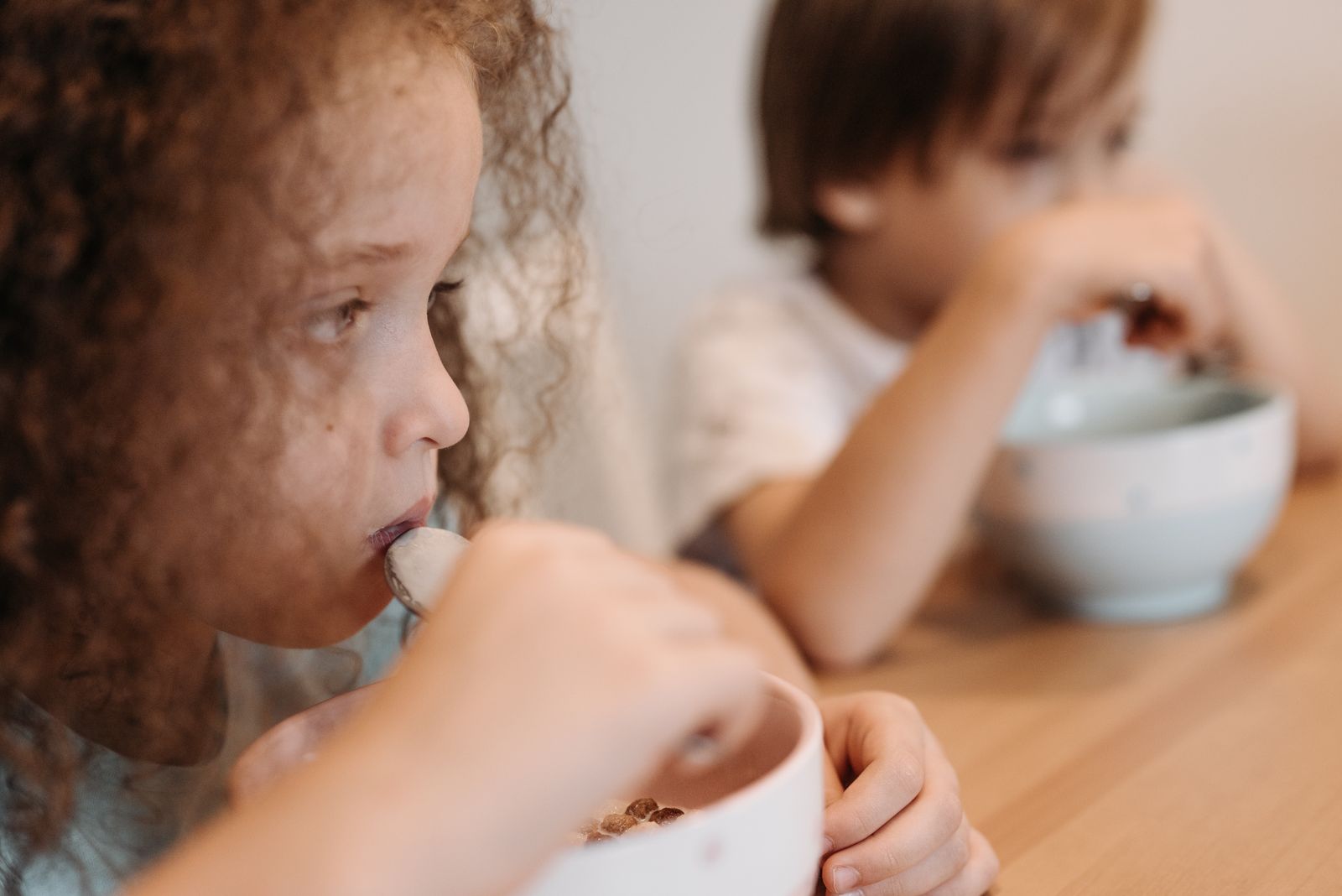 Two children eating cereal at a dining table