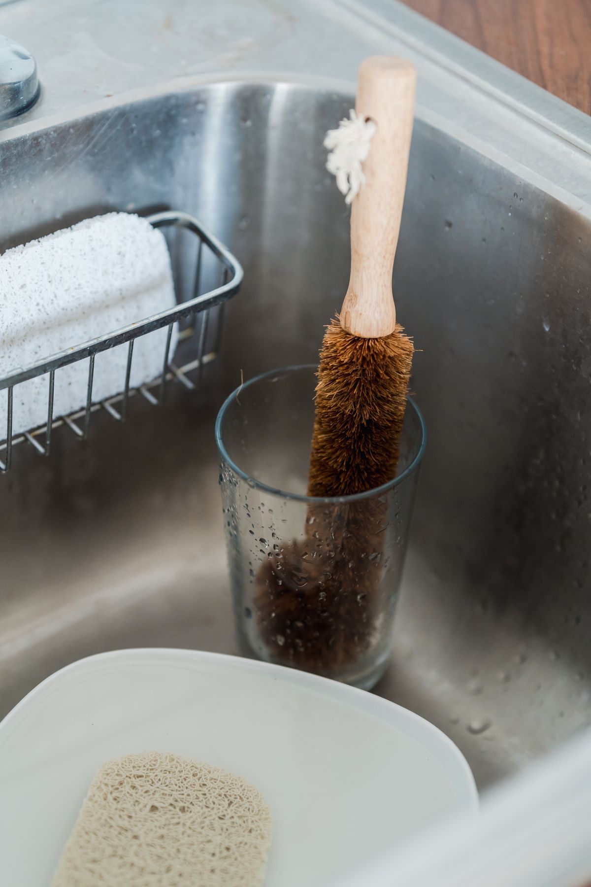 A cleaning brush standing in a glass at a sink