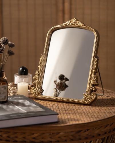 HSDDHOME gold arch mirror standing on a dry tabletop beside books and separate cosmetics