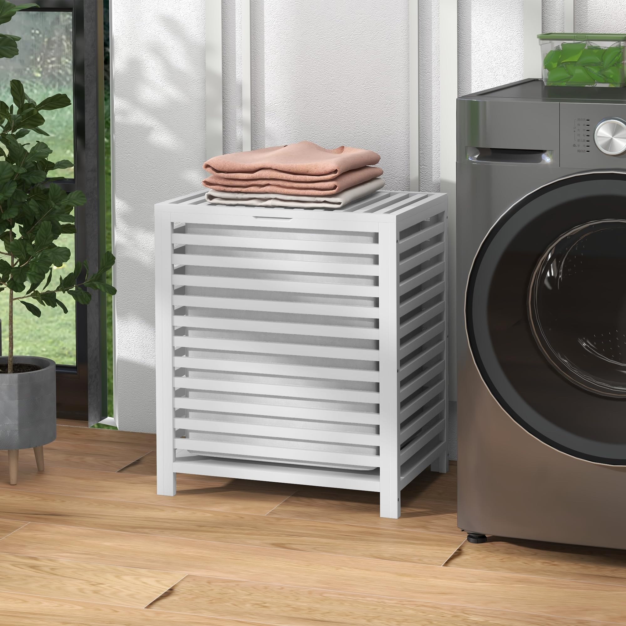Closed hamper beside a washer with folded towels shown as styling props