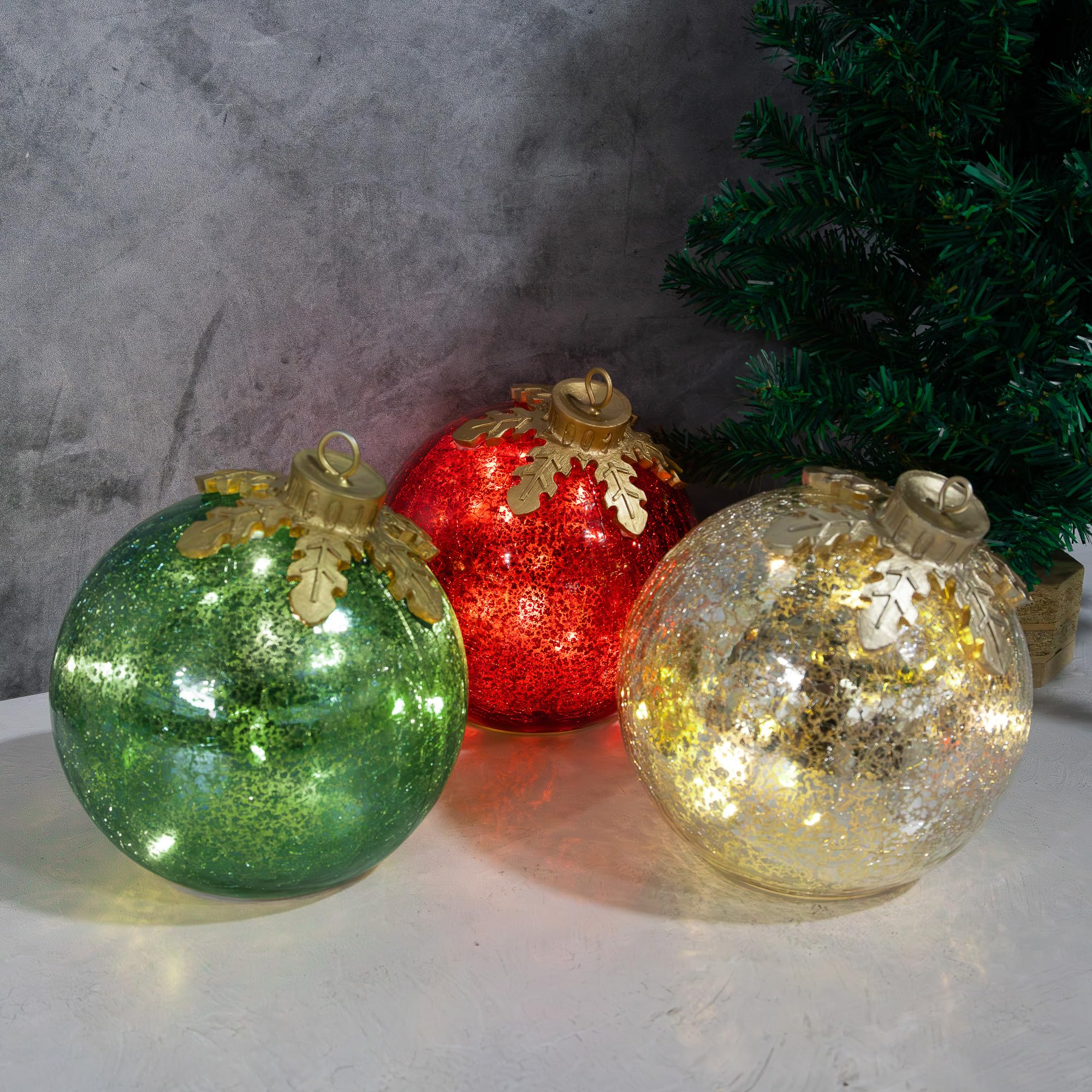 Three lighted crackle-glass globes near a separate tree branch