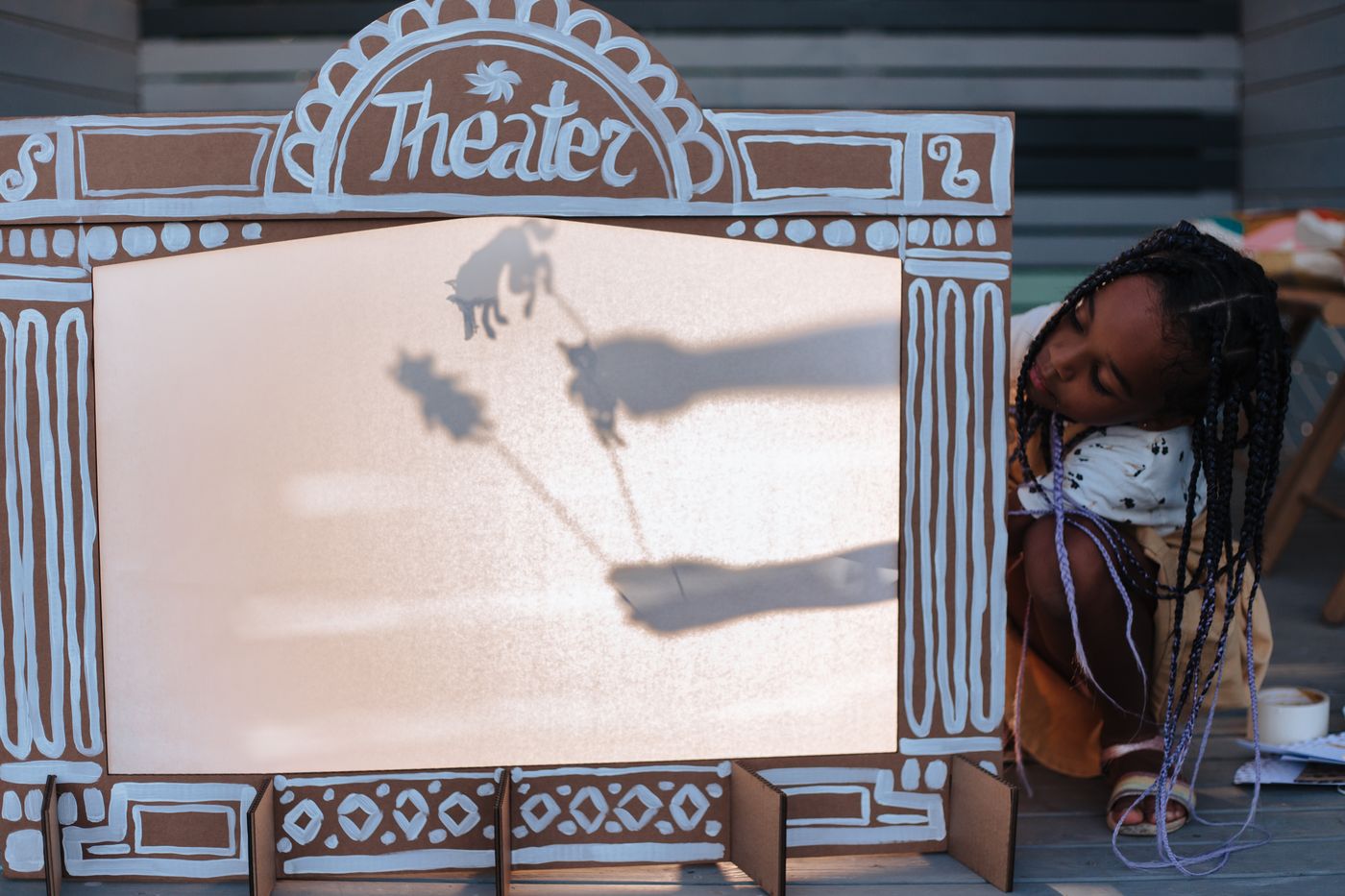 A child performing behind a small shadow-puppet theater