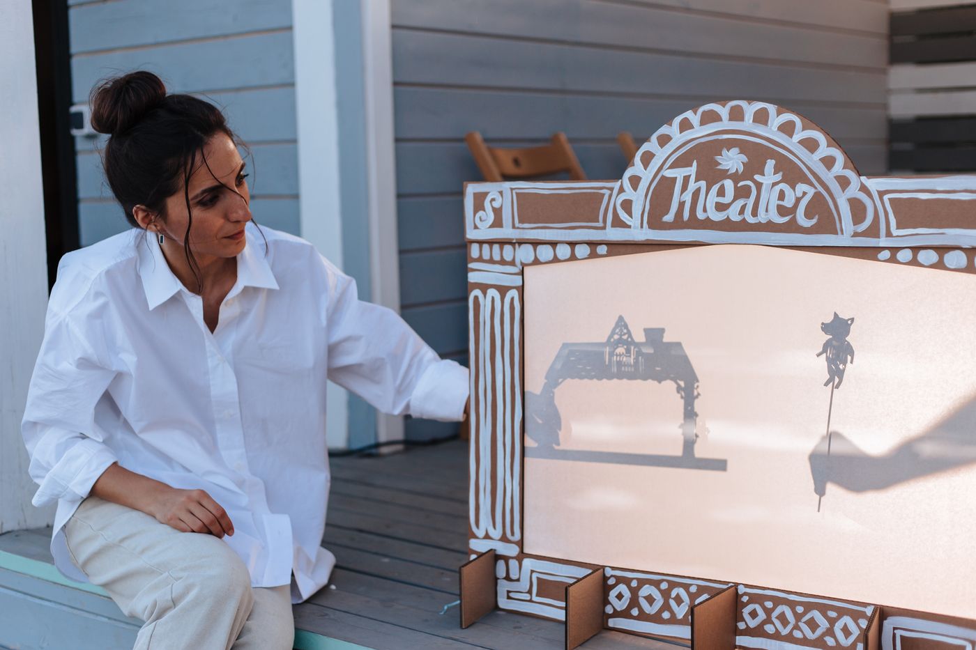 An adult supporting a tabletop shadow-puppet performance