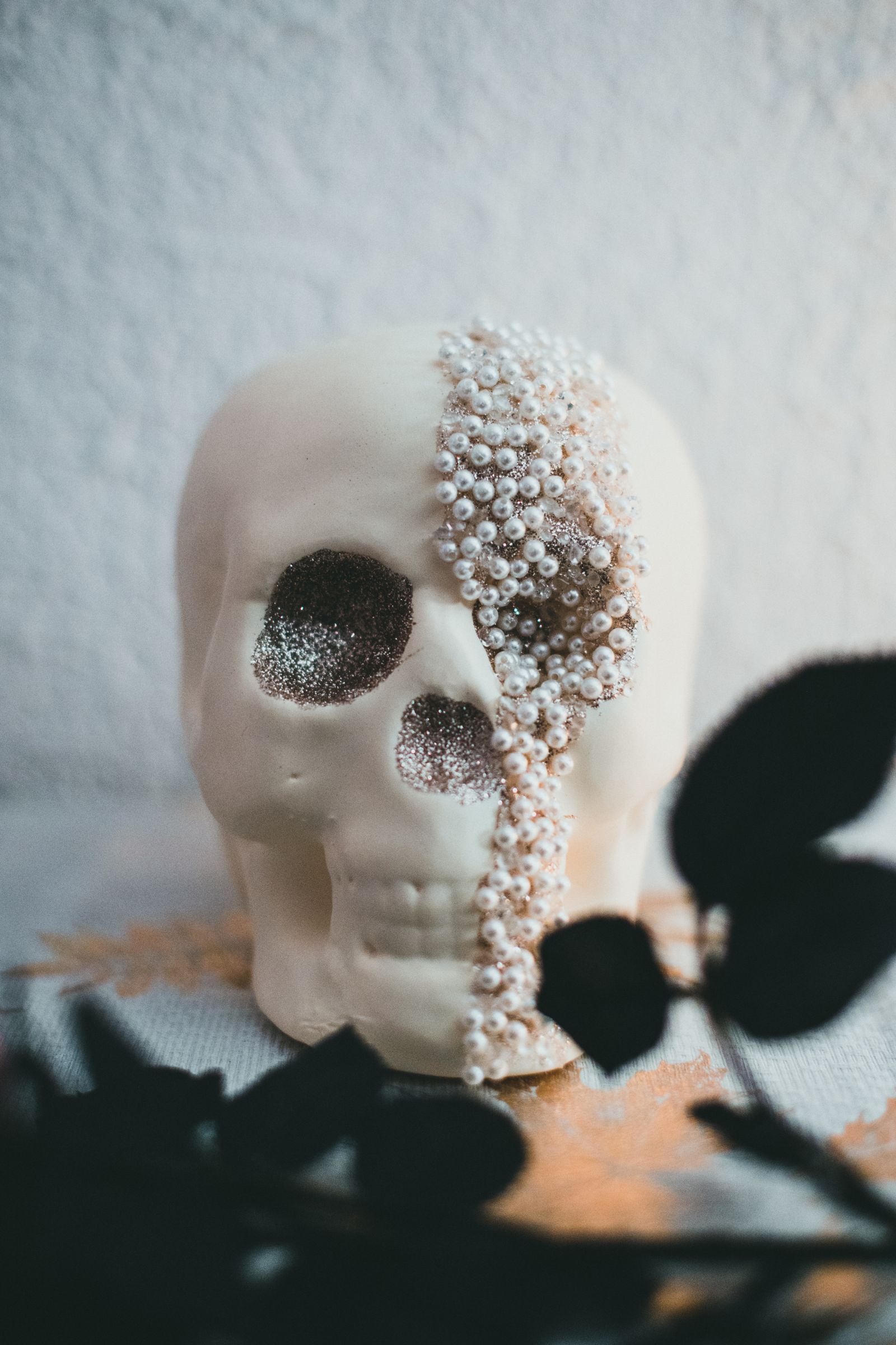 A decorative skull covered in pearls and glitter