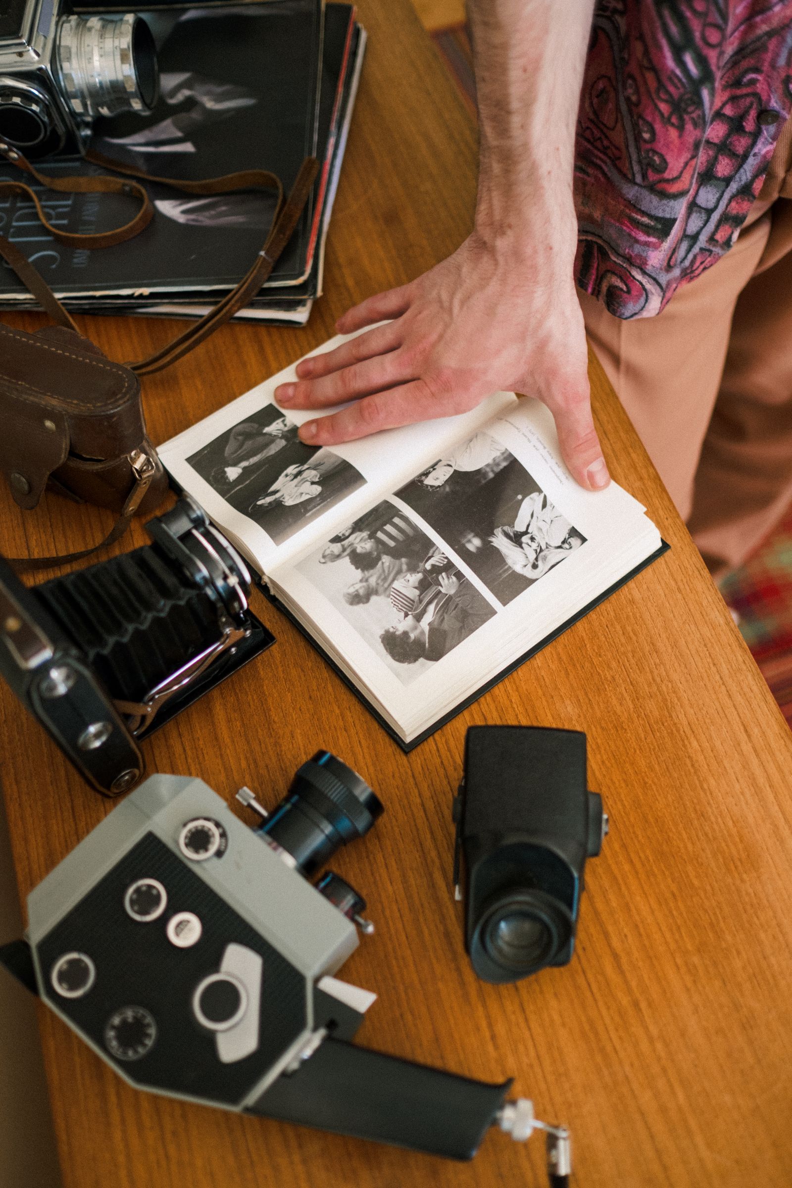 Hands opening a family photograph album beside old cameras