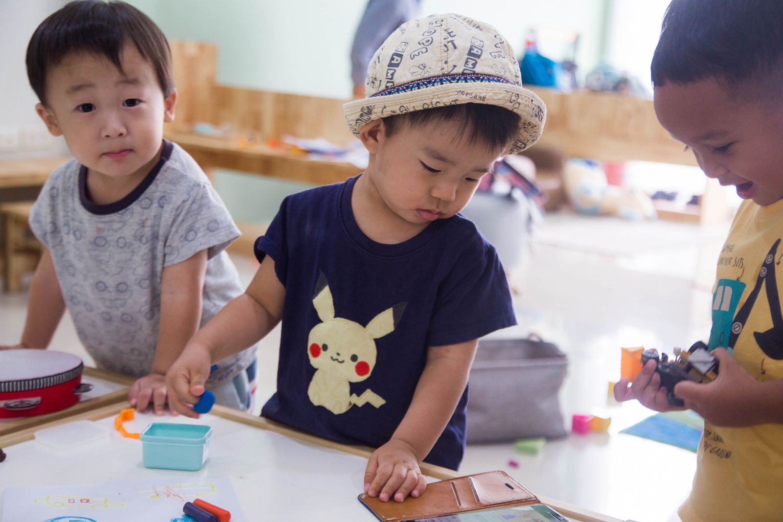 Three children playing with small items at an indoor table