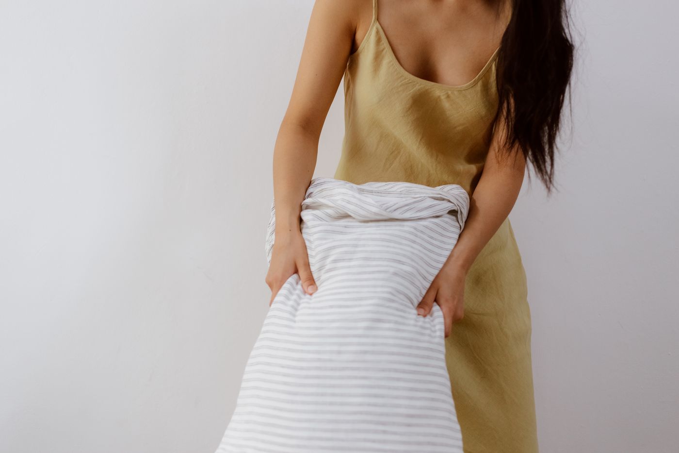 Person holding a pillow in a striped cover