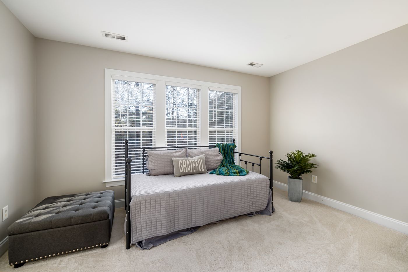Iron-framed daybed with pale textiles in a furnished room