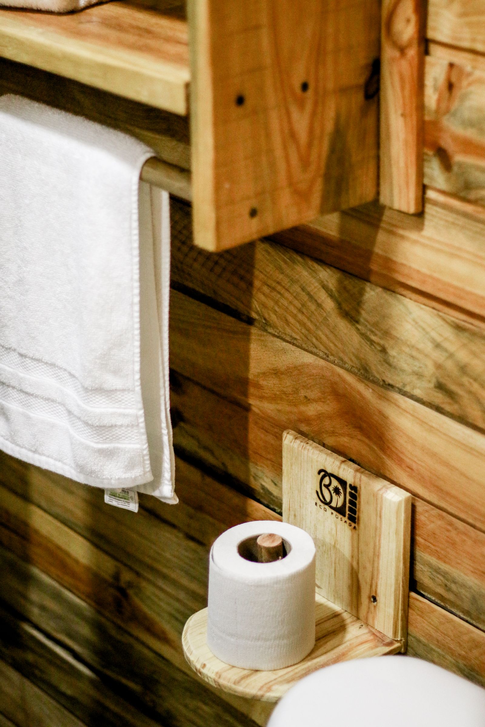 A toilet-paper roll and hand towel in a wooden bathroom