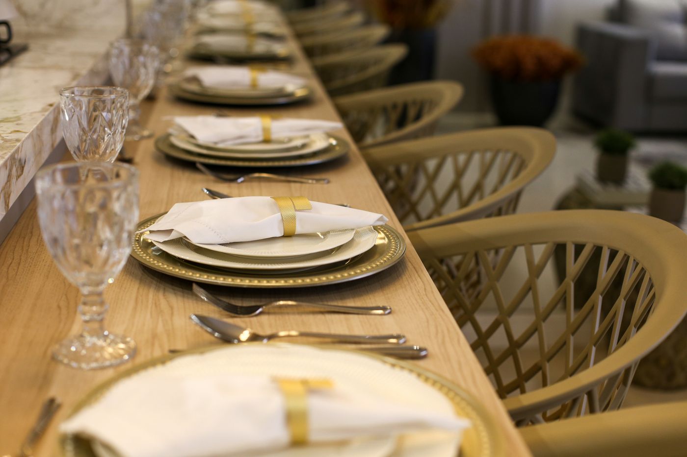 White cloth napkins and gold tableware arranged along a dining table