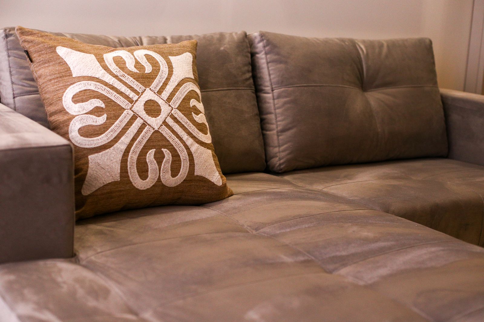An embroidered decorative cushion on a brown sofa