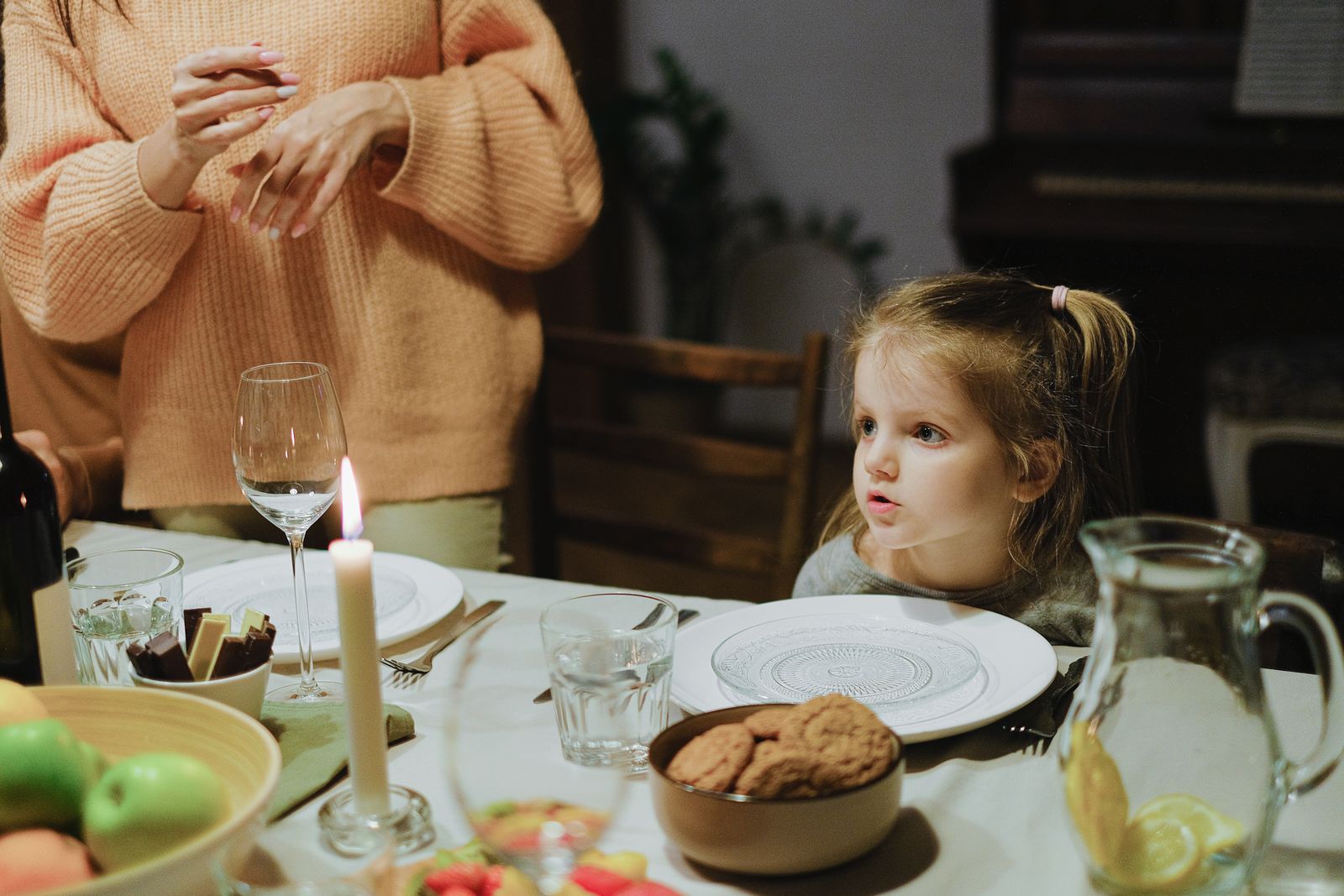 A child seated at a family table with an adult nearby