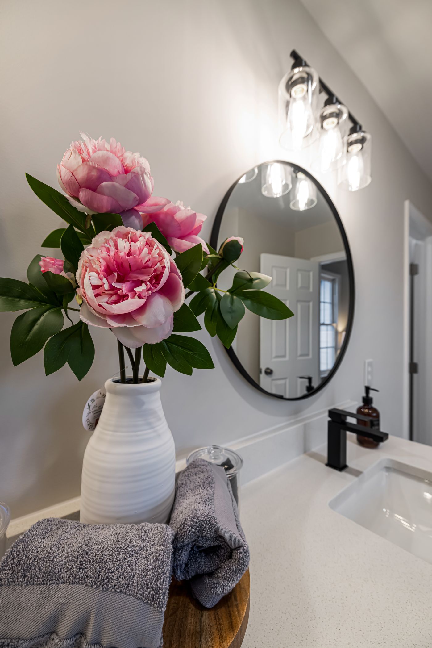 Flowers in a light decorative vase beside a bathroom sink