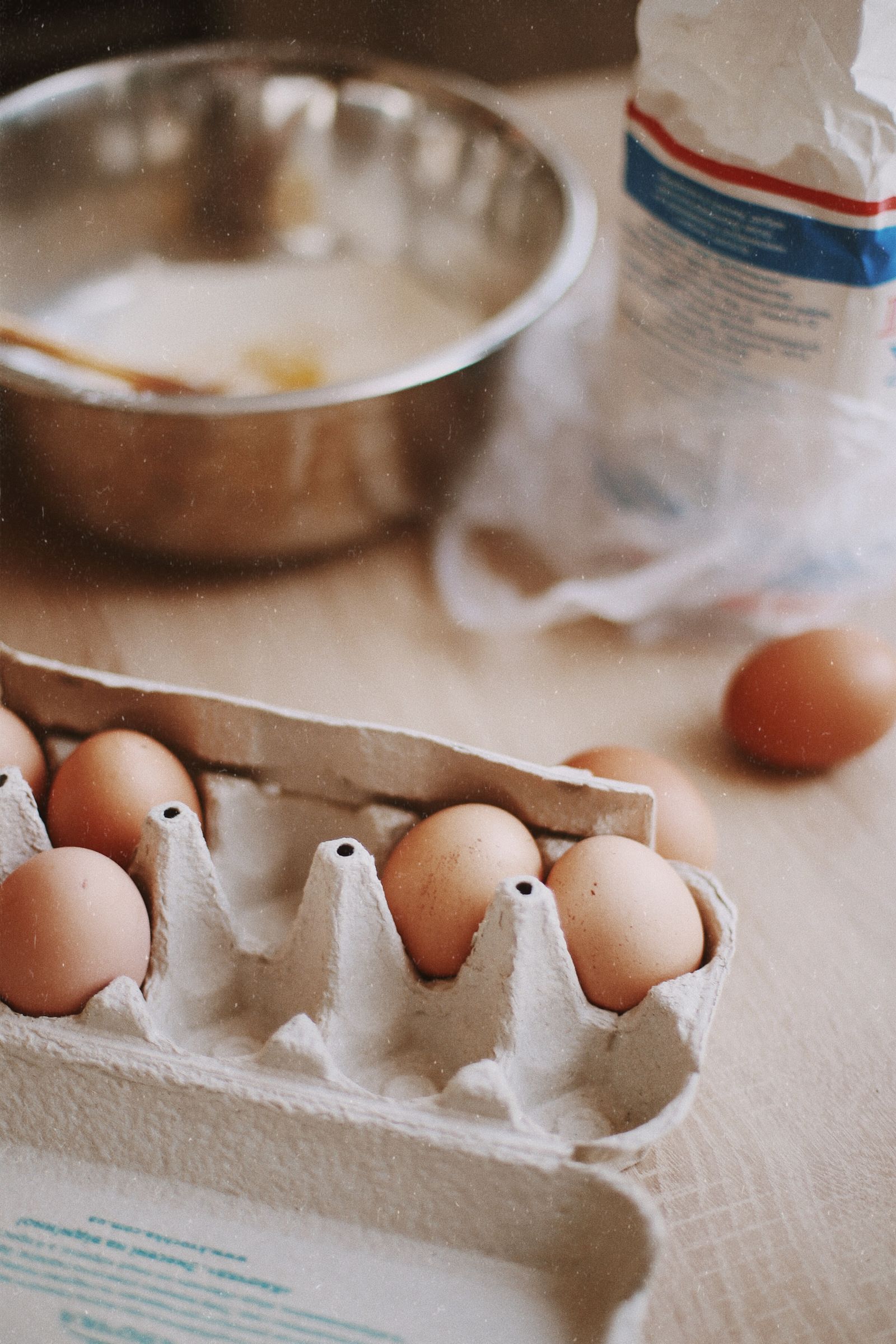 Eggs, flour, and a glass jug on a baking work surface
