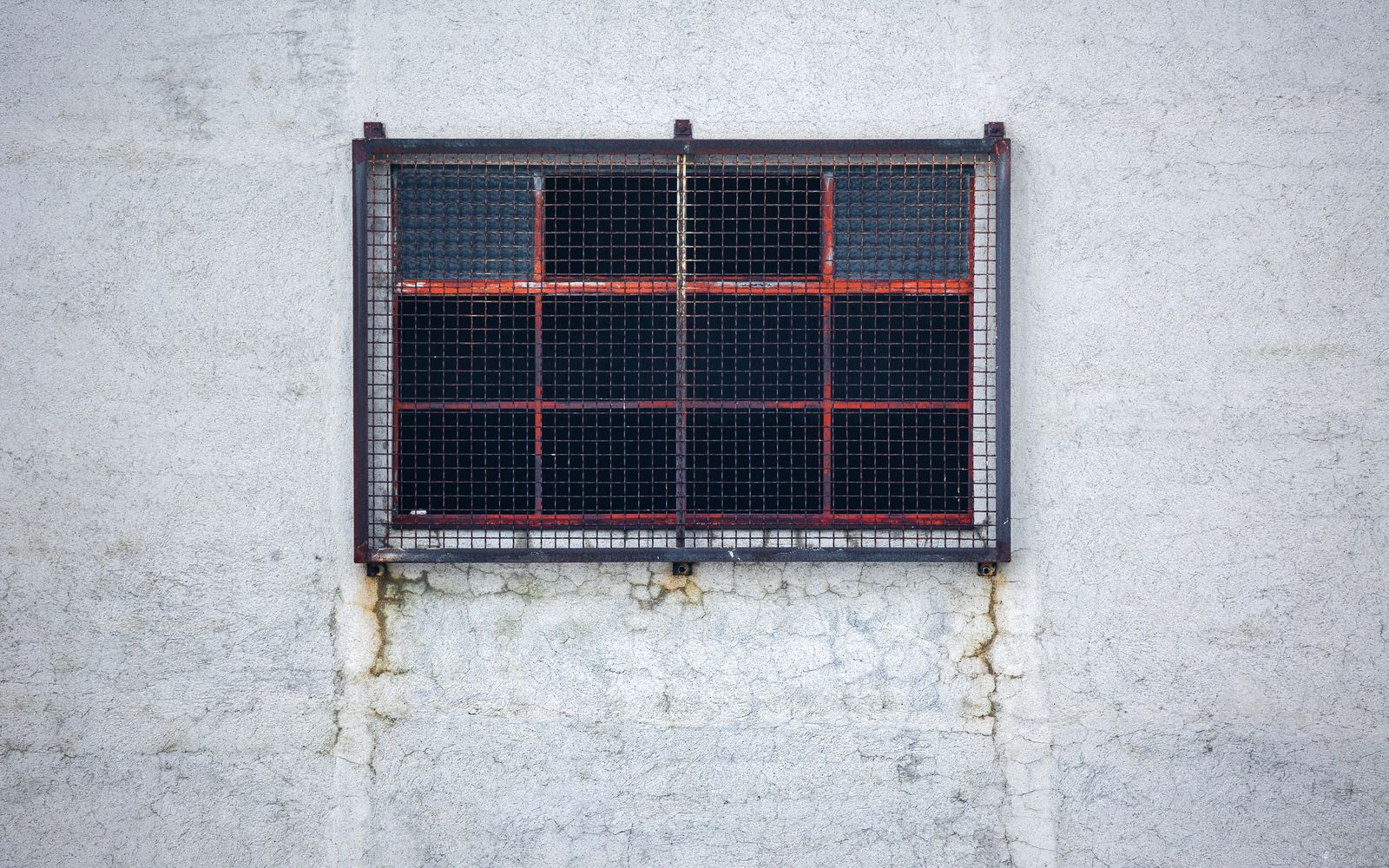 A small window with a metal grille and mesh layers