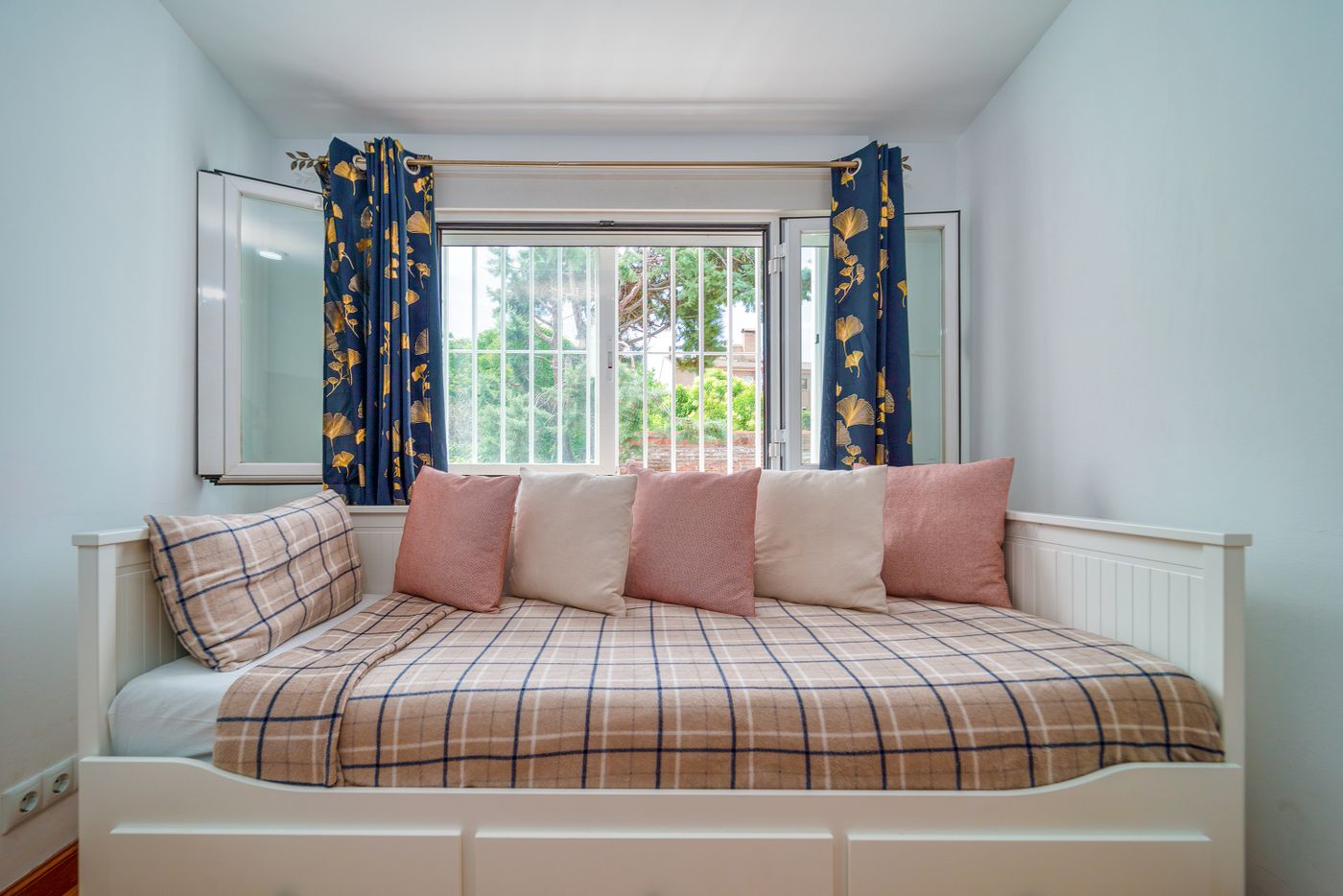 White daybed with checked bedding and pink cushions