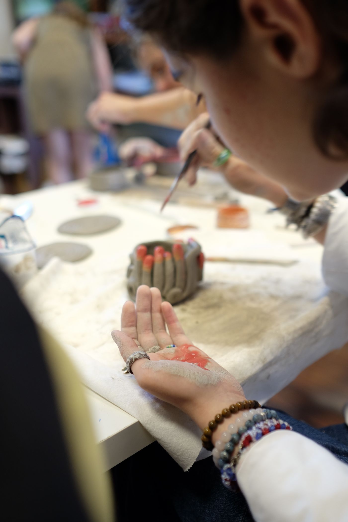 Child using a paintbrush at a pottery table; illustrative finishing-supply context