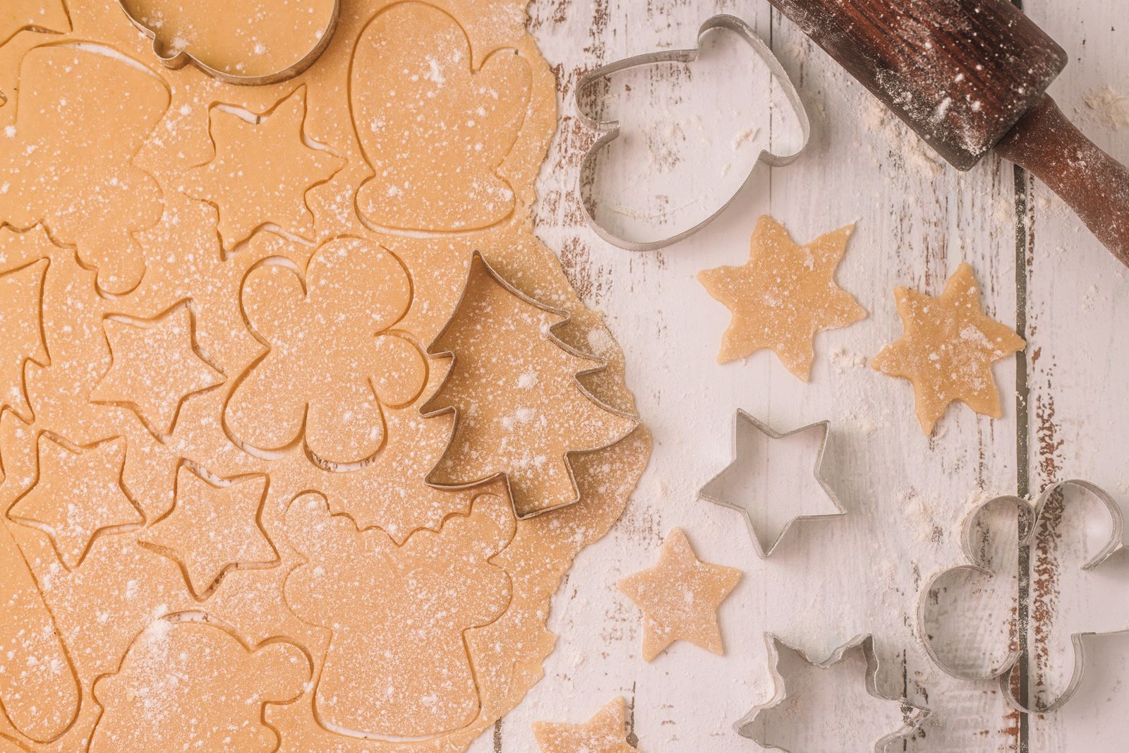 Cookie cutters beside shapes cut from pale dough