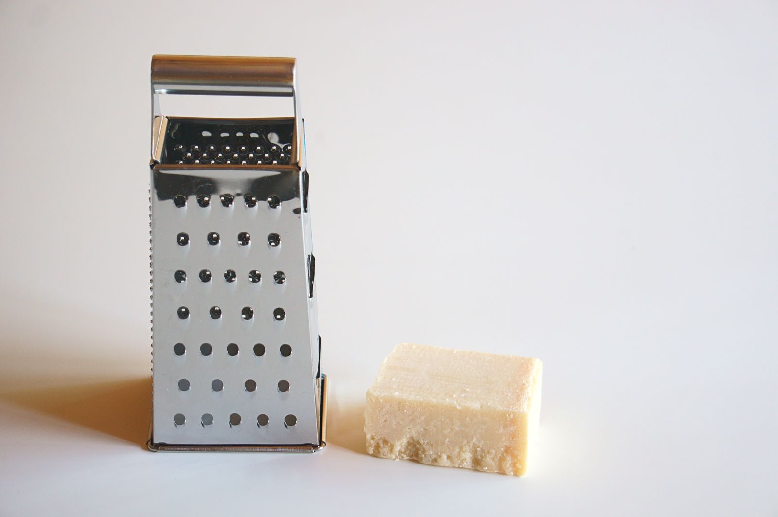 A box grater beside a block of cheese