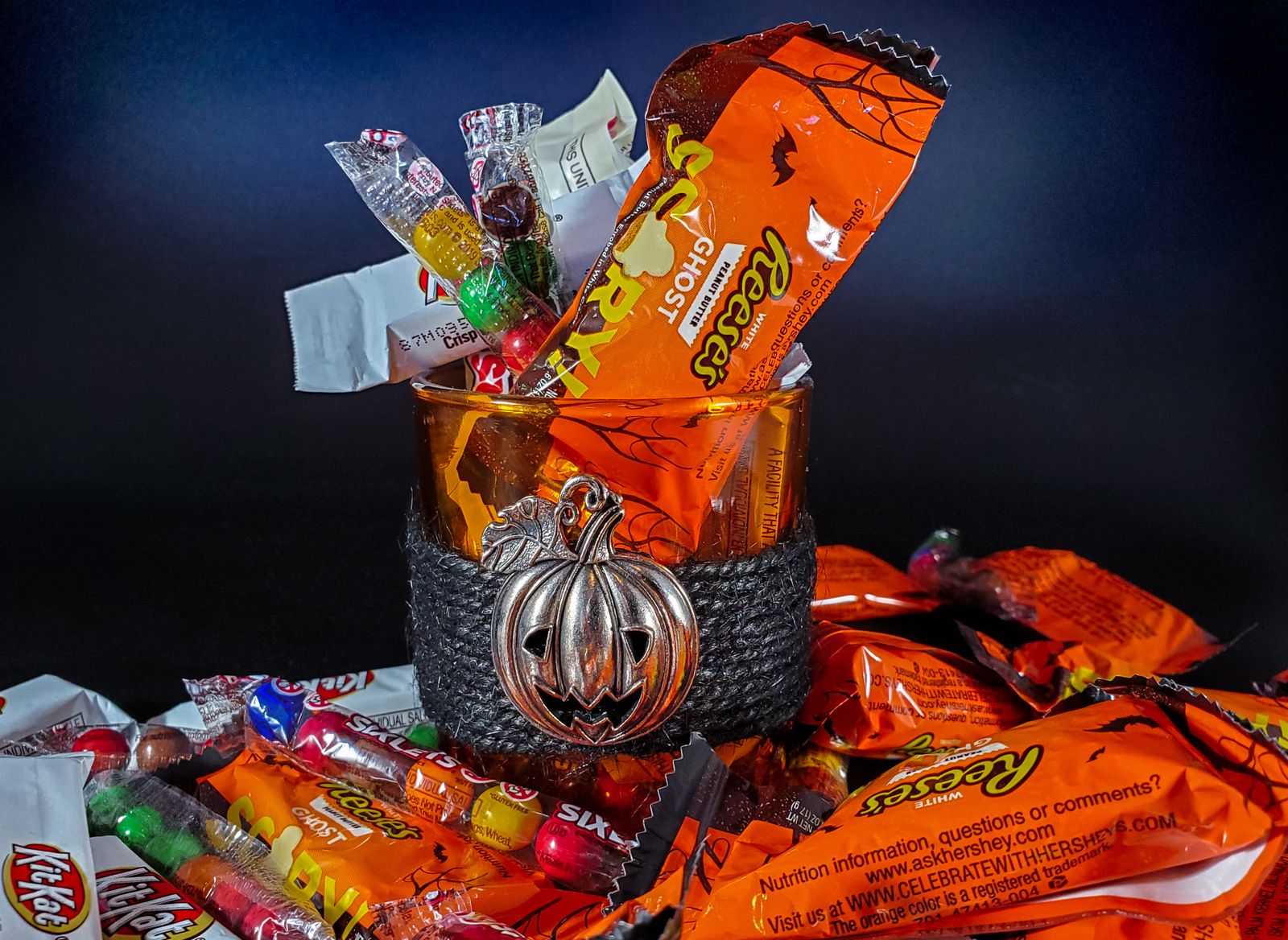 Wrapped candies in a glass container with a pumpkin emblem