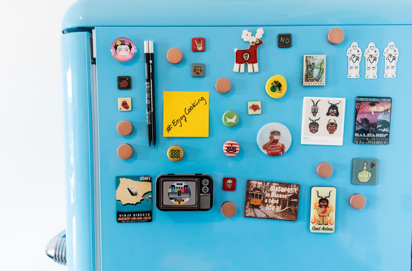 A blue refrigerator door with separate small magnets and notes