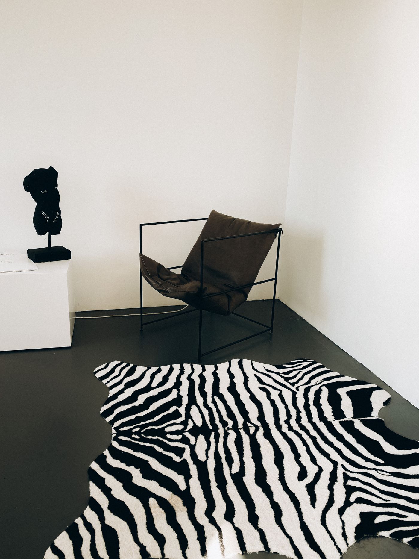 A black chair near a contrasting striped rug