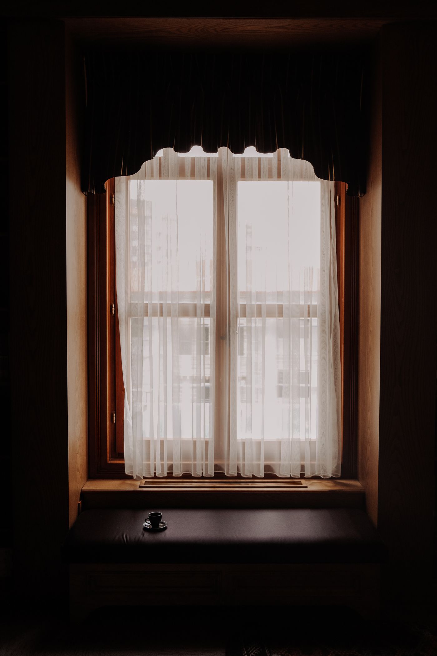 A window with a light curtain and visible wood frame