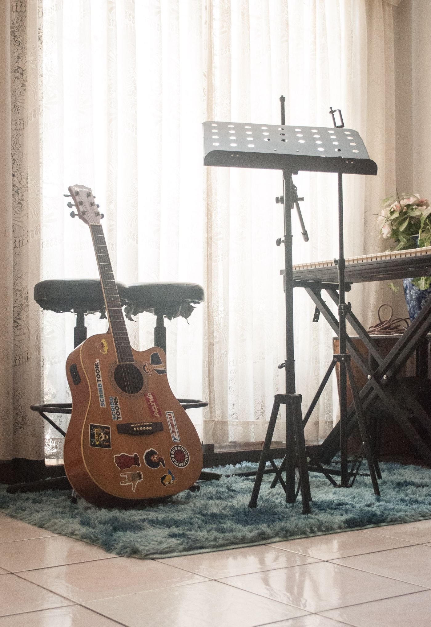Guitar and music stand arranged beside a stool