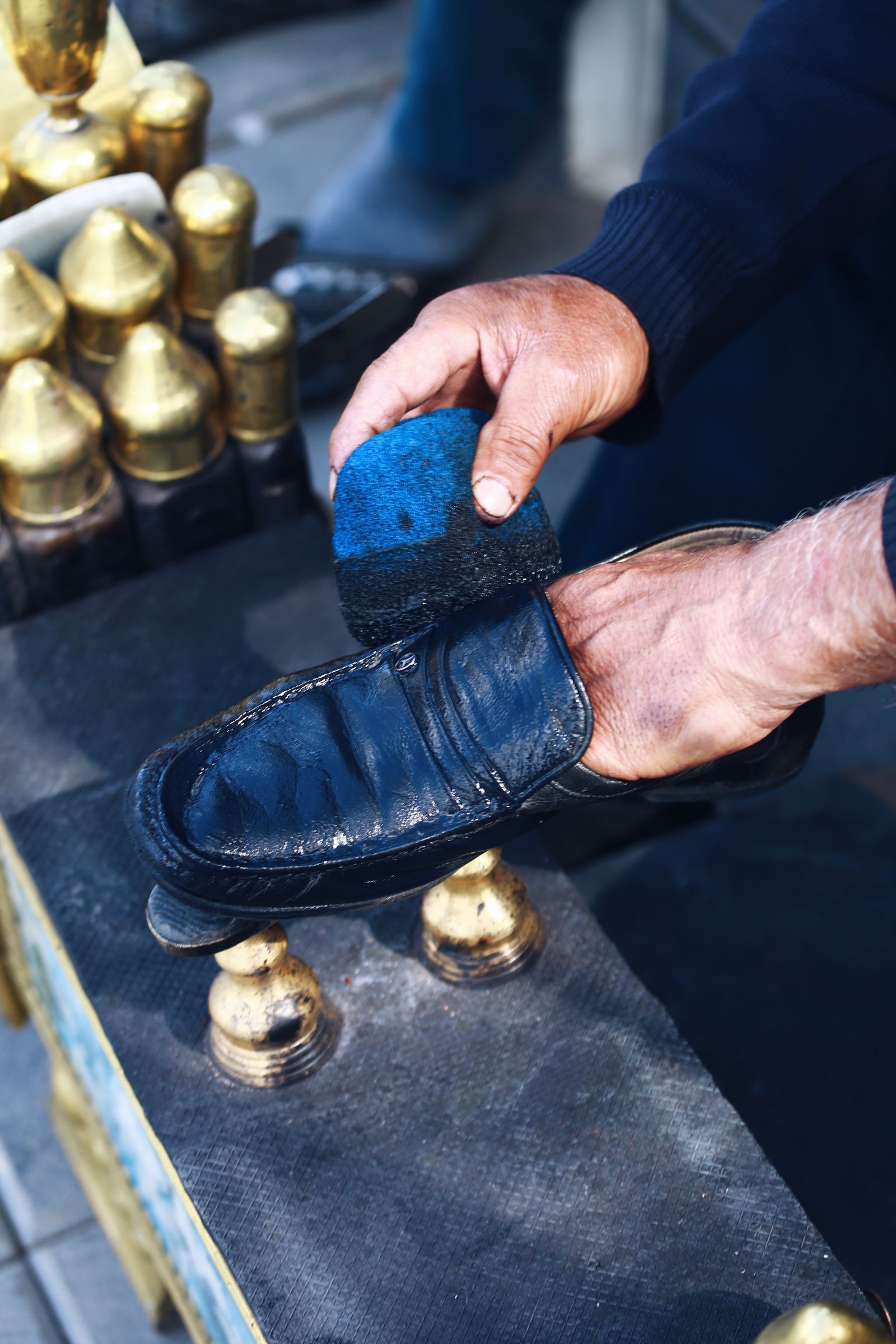 Hands using a brush on a dark leather shoe