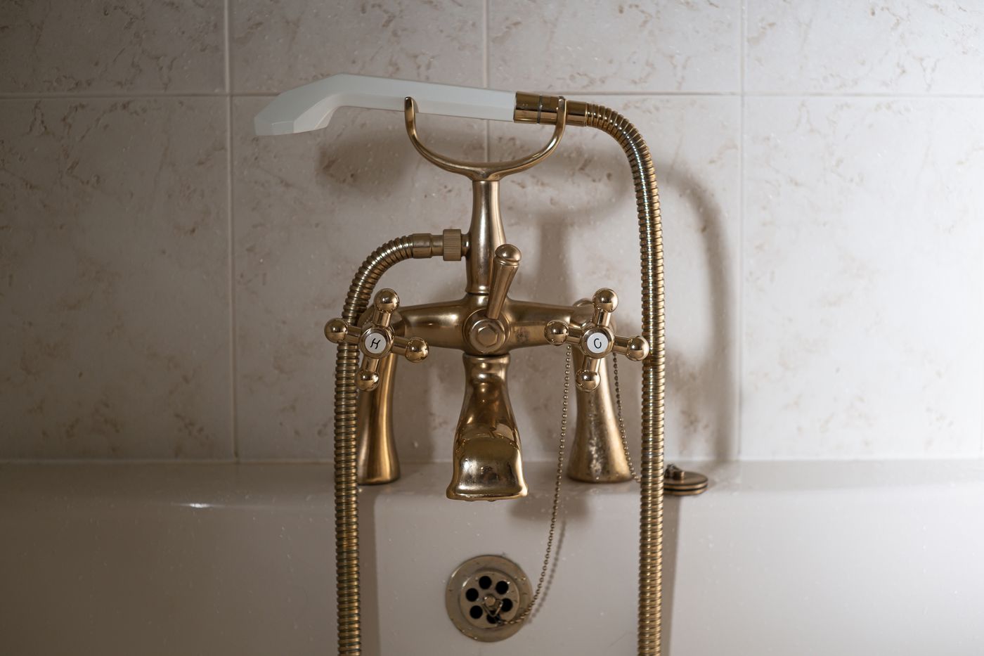A brass-colored bath fitting with cross handles