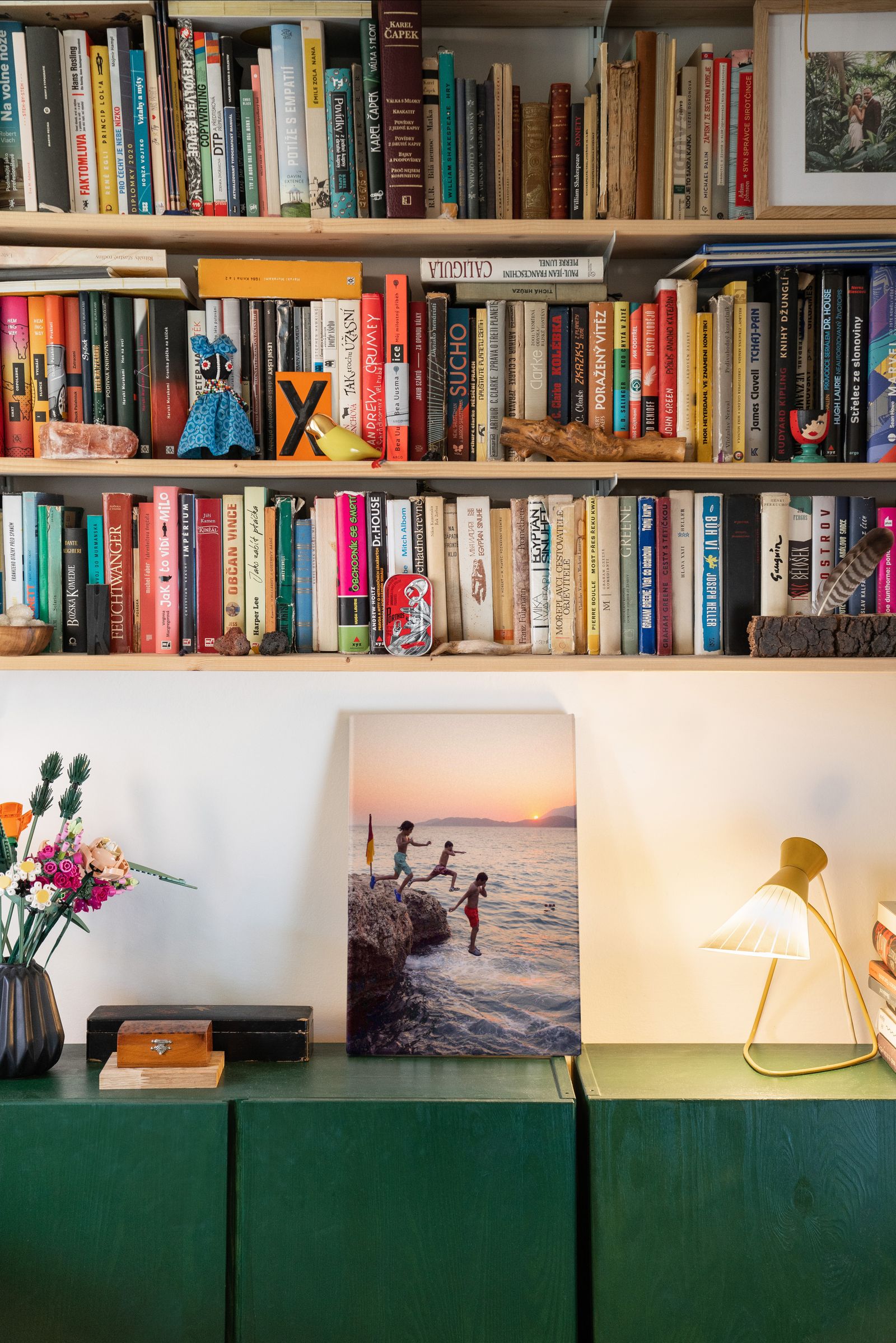 A living-room bookshelf with art and warm lighting