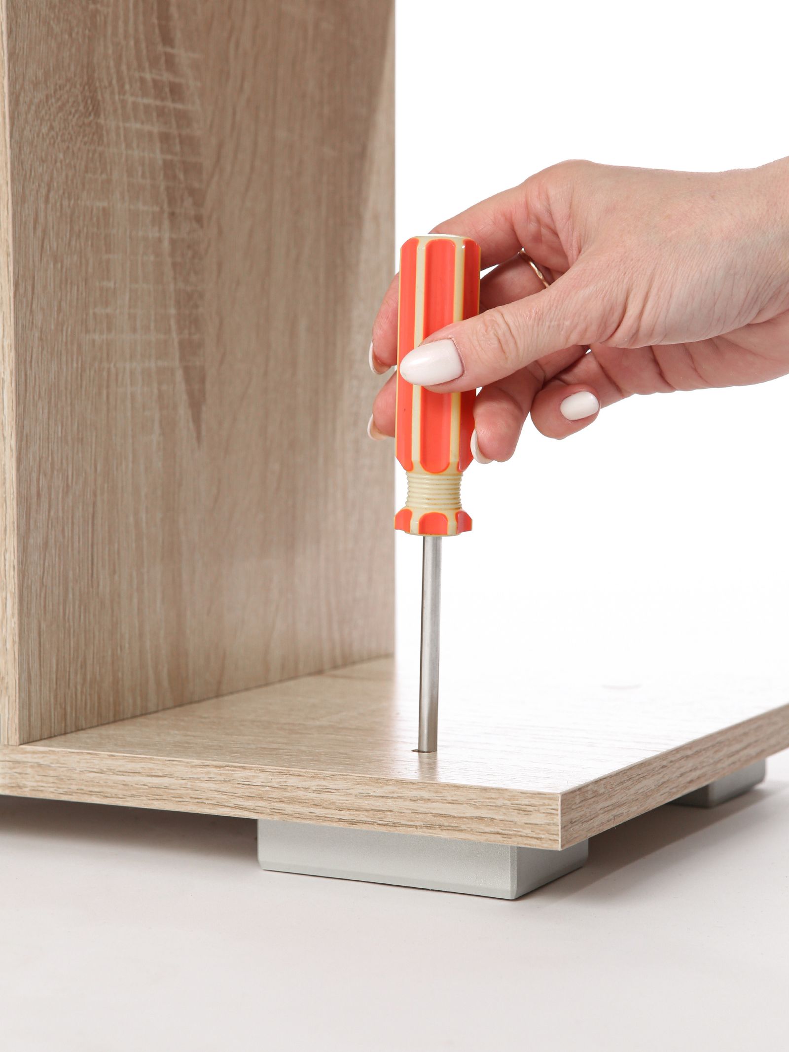 A hand using a screwdriver on a furniture panel