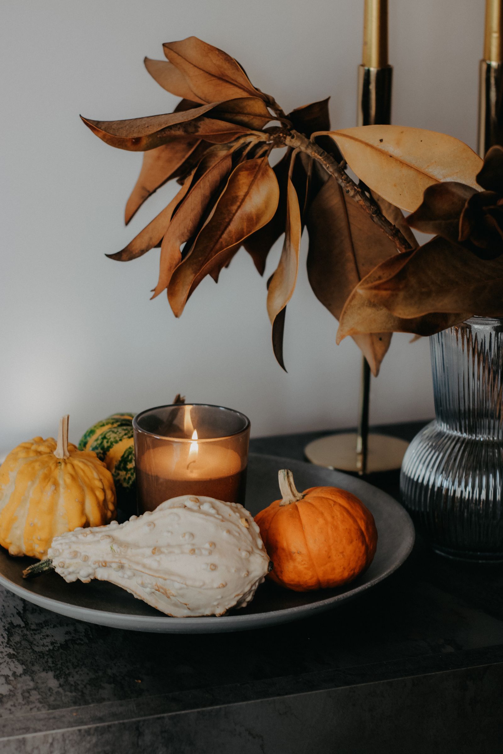 Pumpkins and a candle on a decorative plate