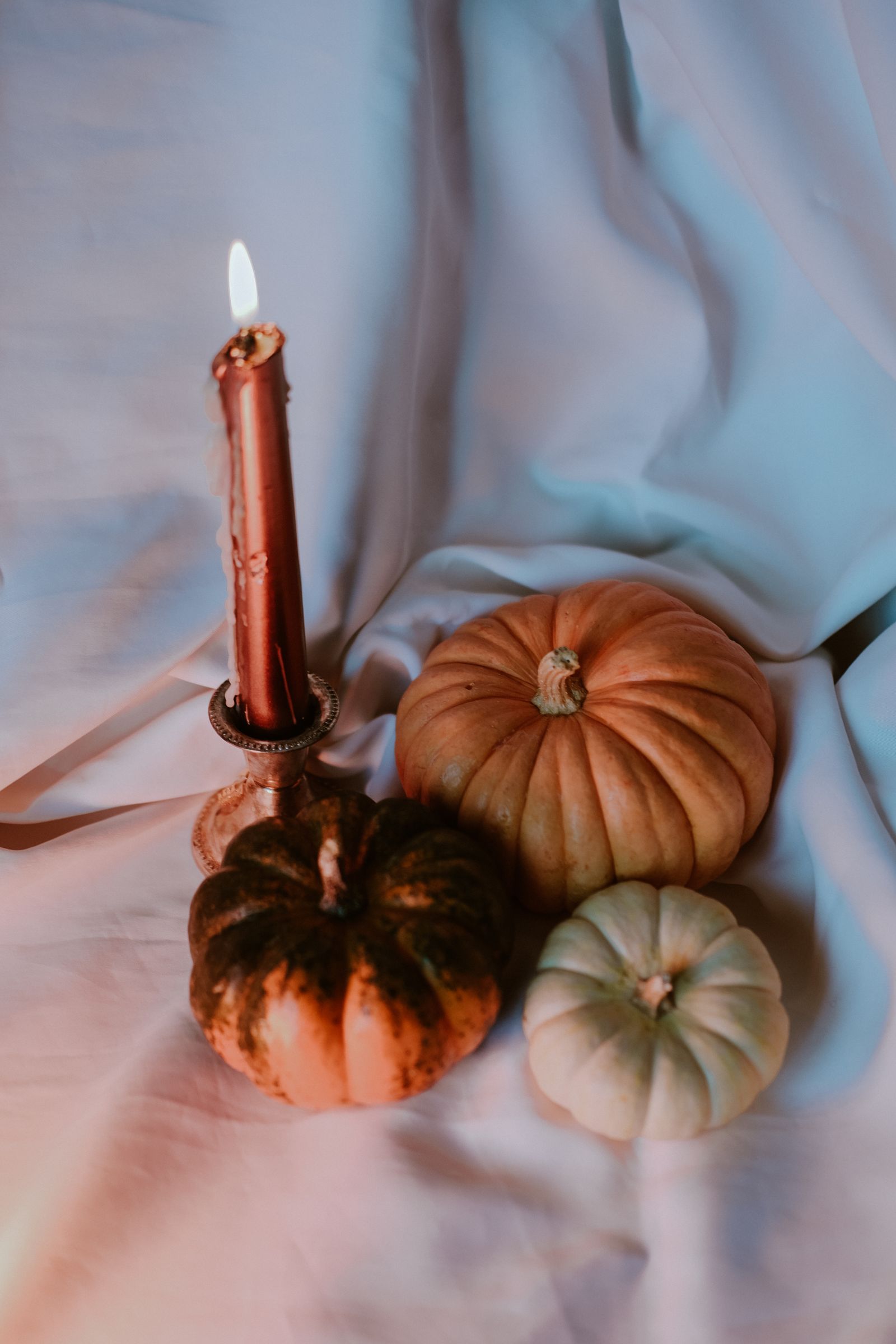 Small pumpkins beside a candle