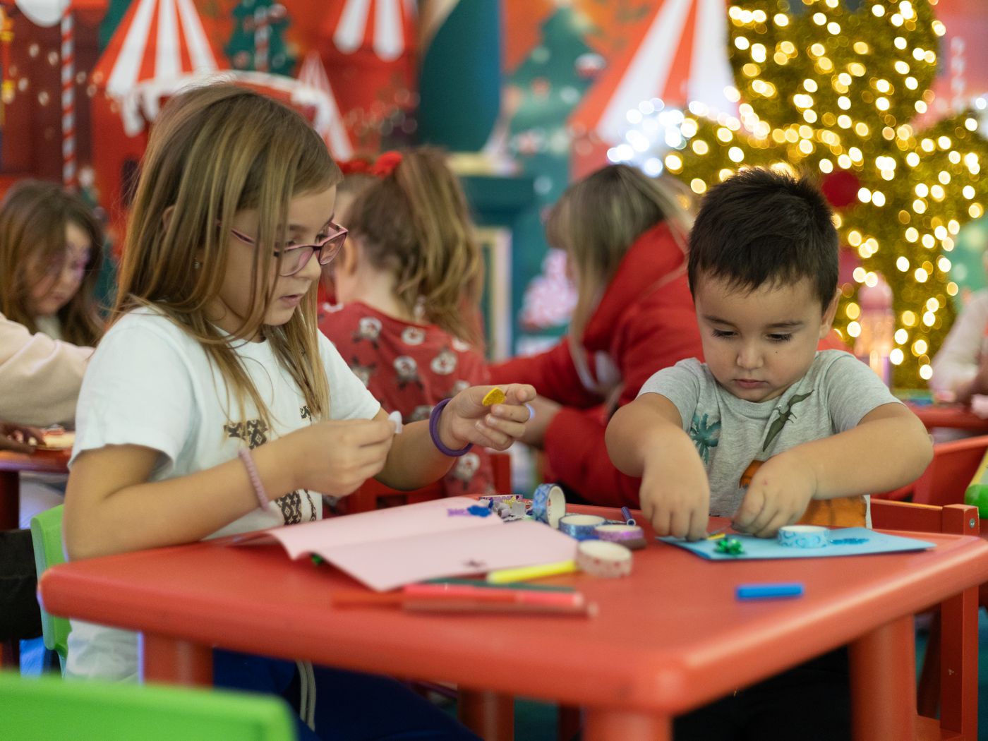 Children making individual paper crafts around a shared table