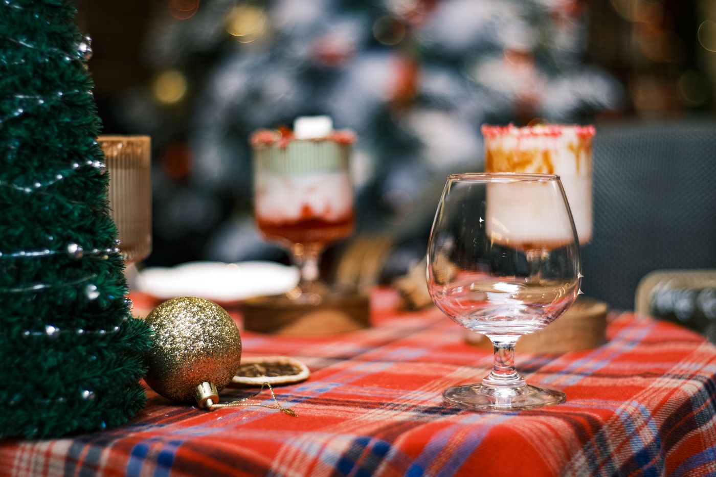 A clear wineglass and festive decorations on a plaid tablecloth