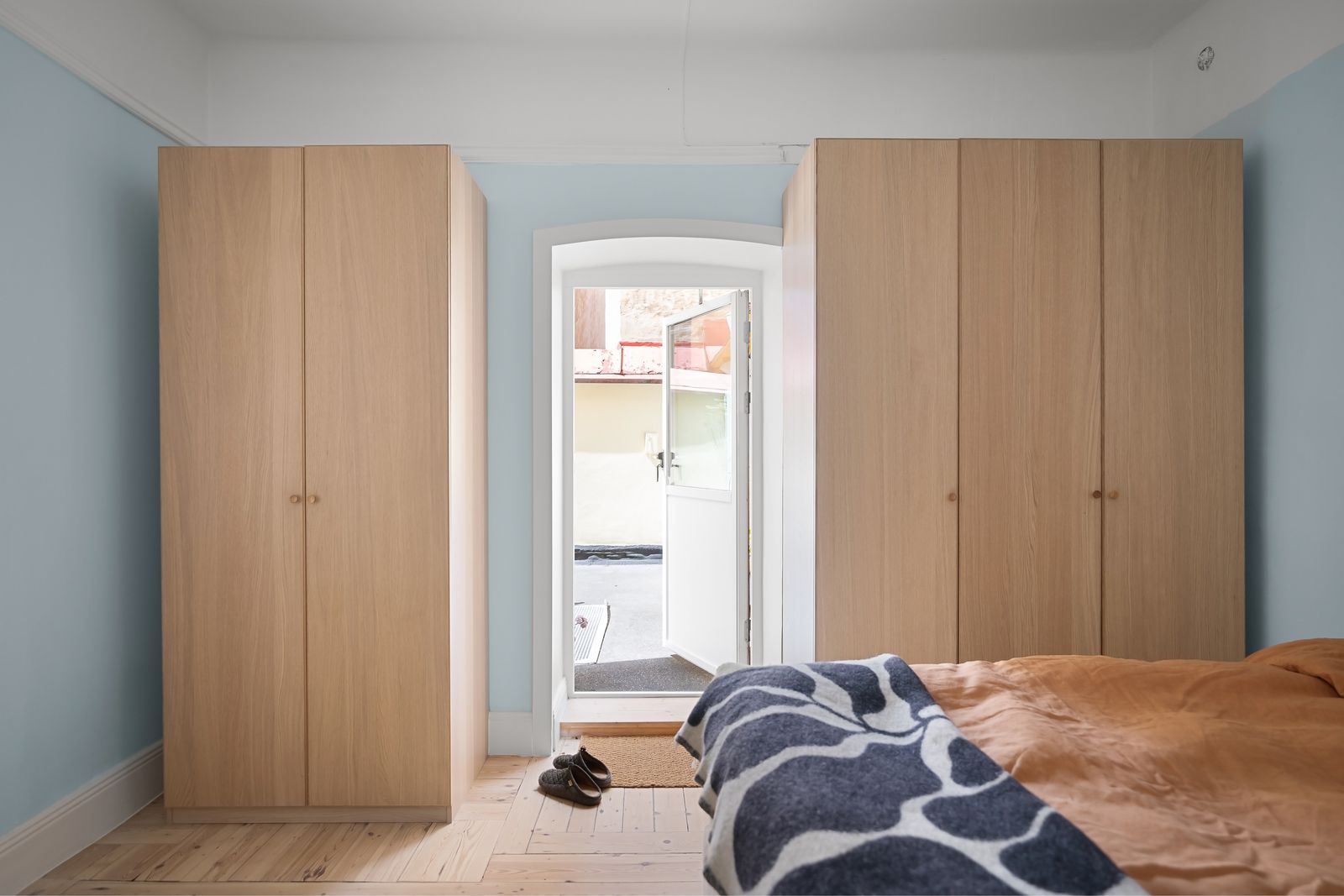 A bedroom with wood wardrobes and an open doorway