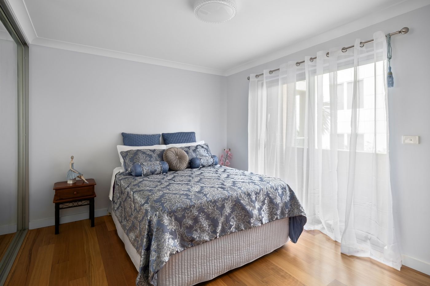 Bedroom combining blue patterned bedding with pale walls