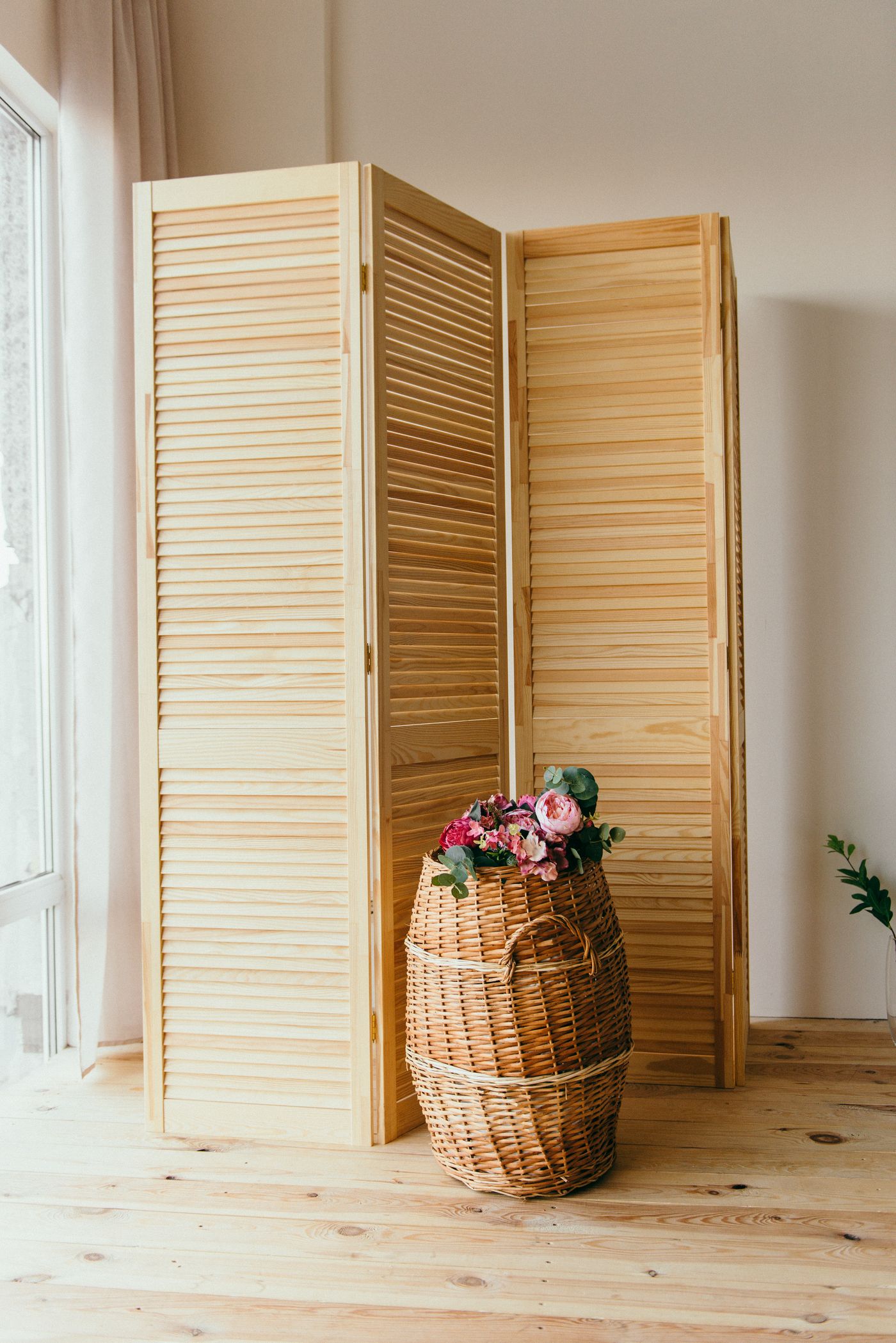 A wooden folding screen standing beside a basket