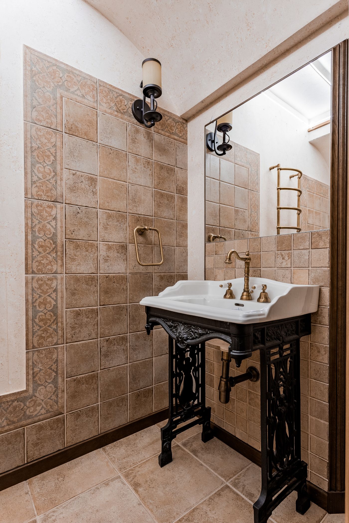 A bathroom basin and mirror with metallic fixtures