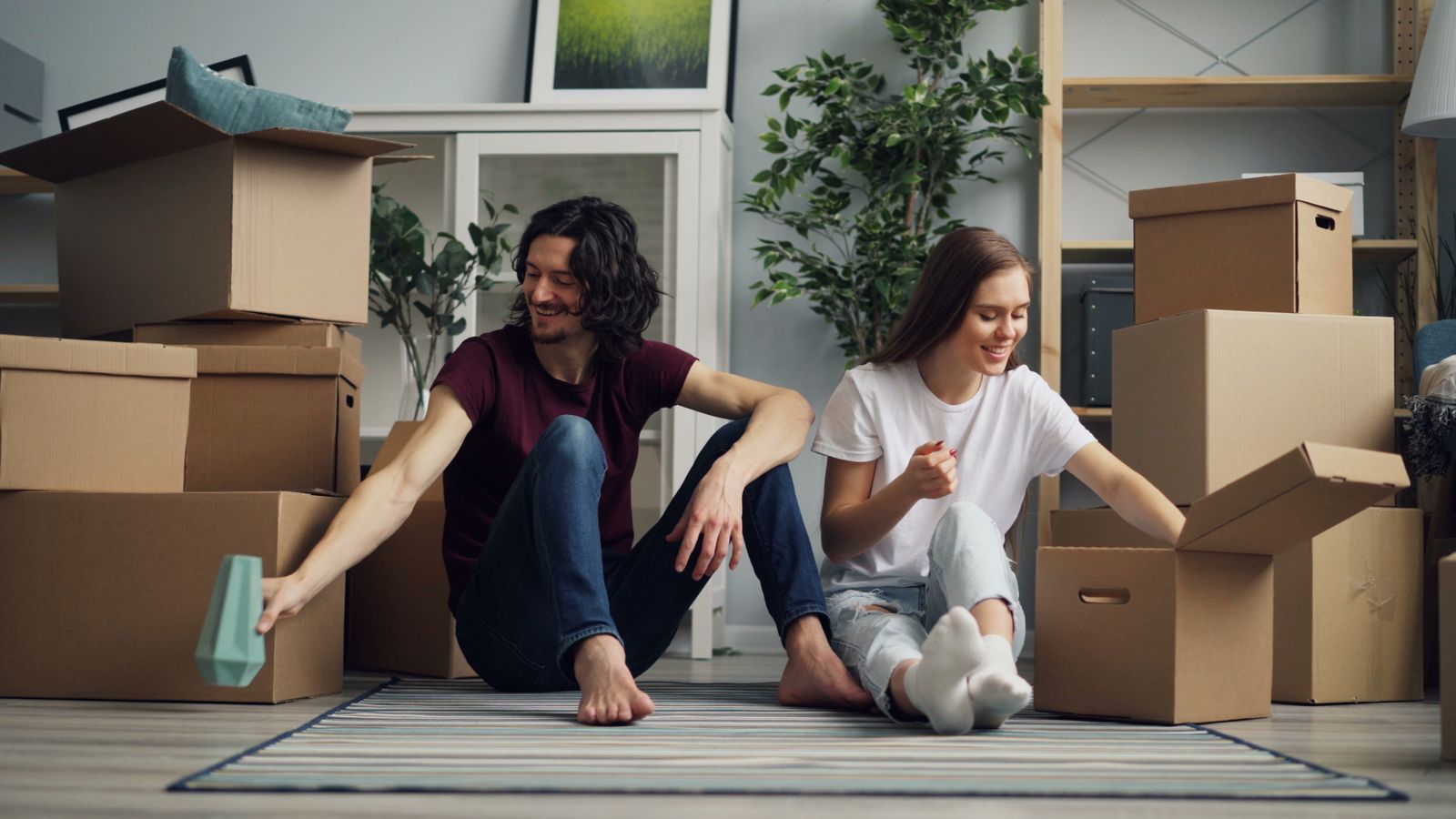 Two adults sitting among boxes in a living room