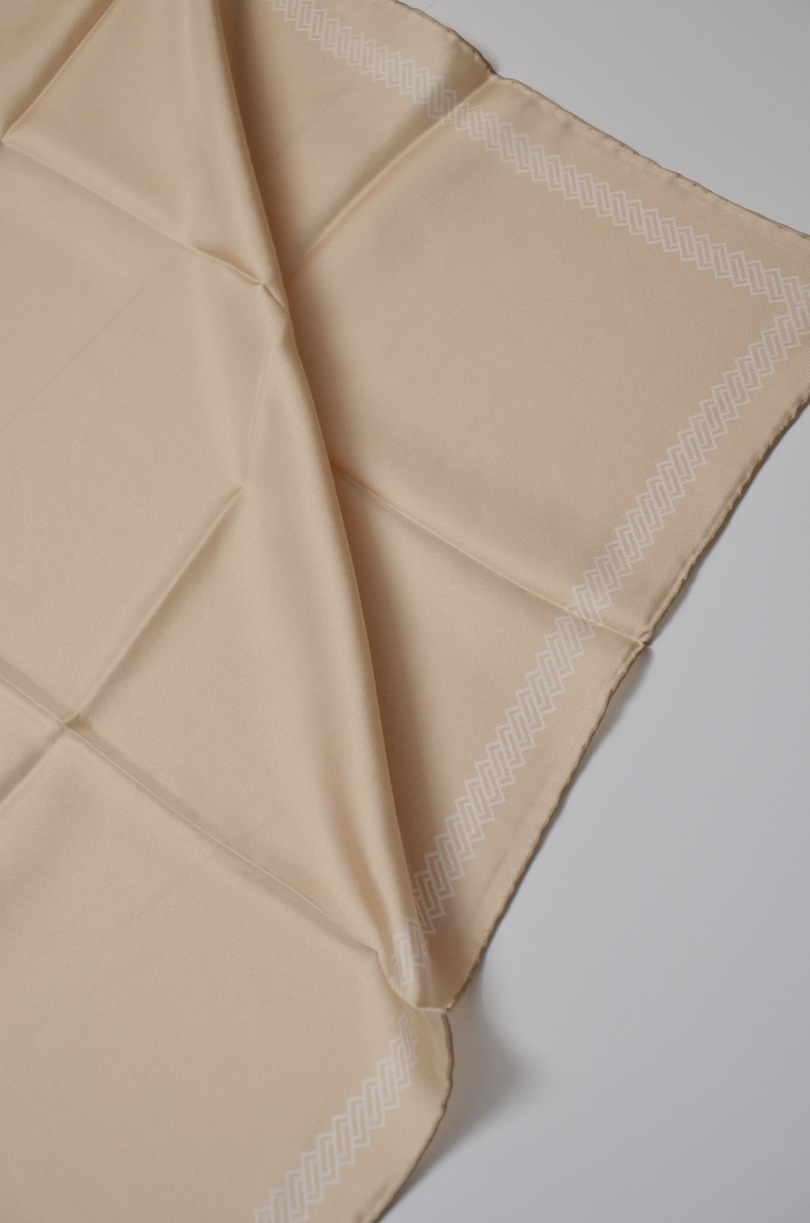A pale embroidered textile with visible folds