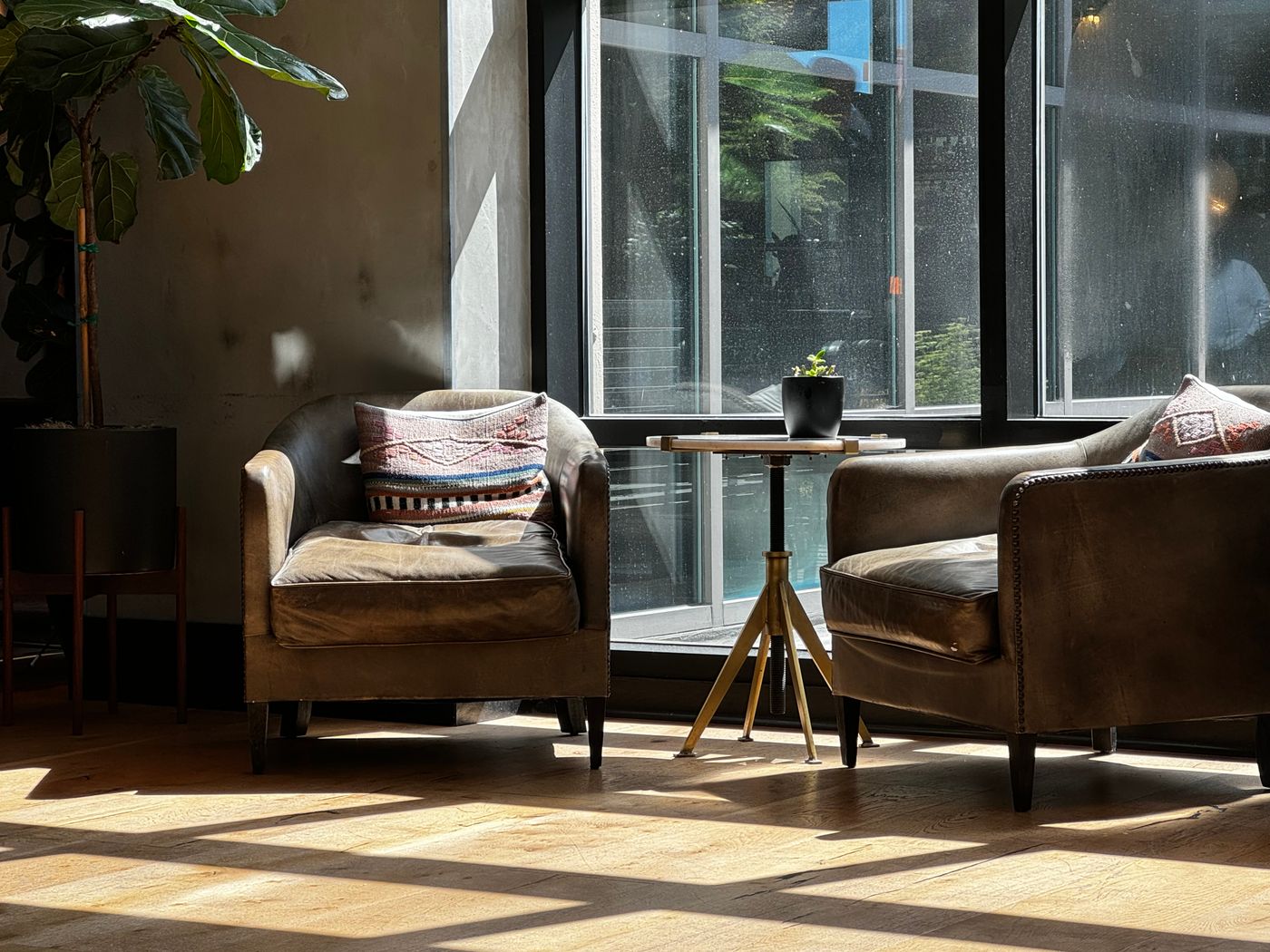 Two armchairs facing a small shared table beside windows
