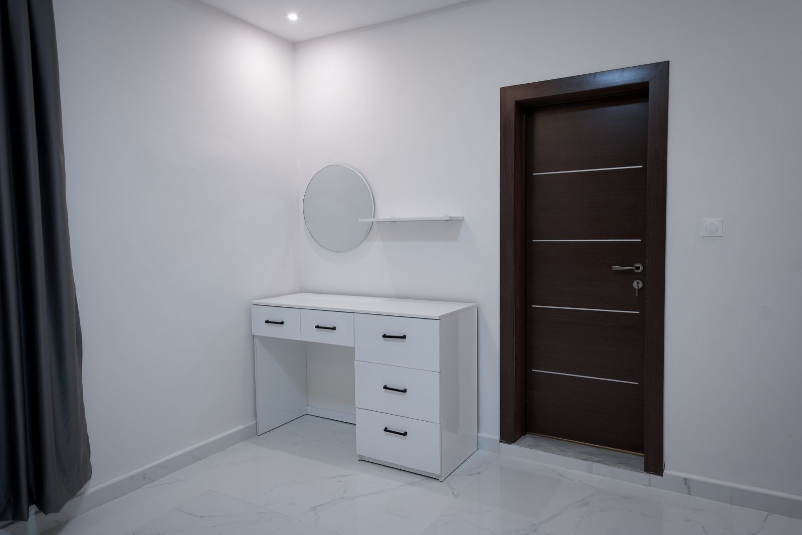 A white dresser beside a dark interior door