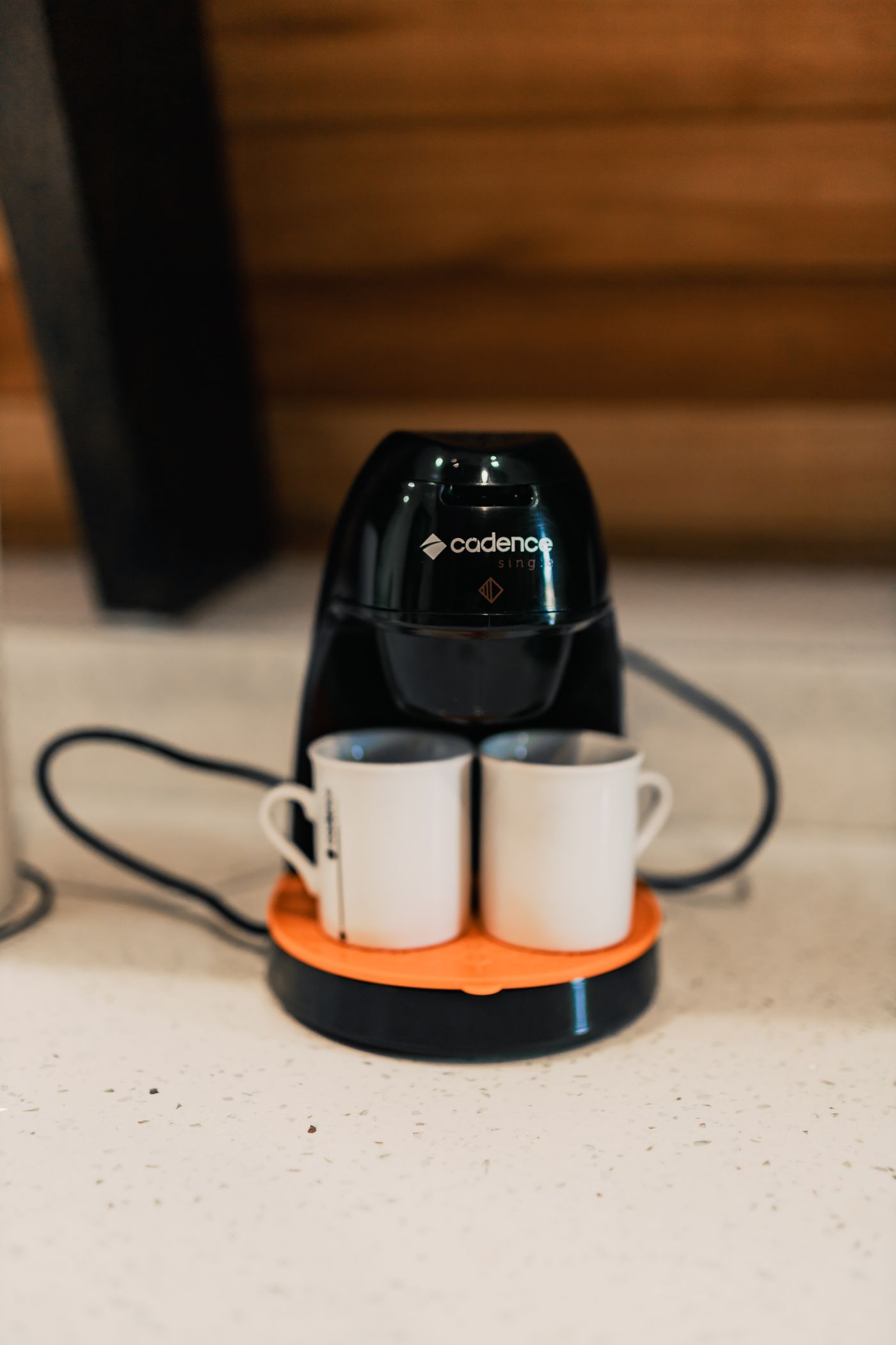 A compact coffee maker with two cups on top