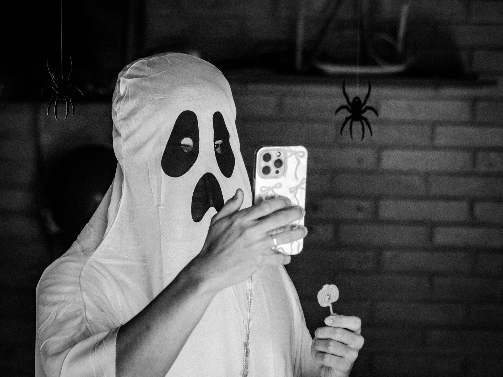 A person in a ghost costume taking a phone selfie