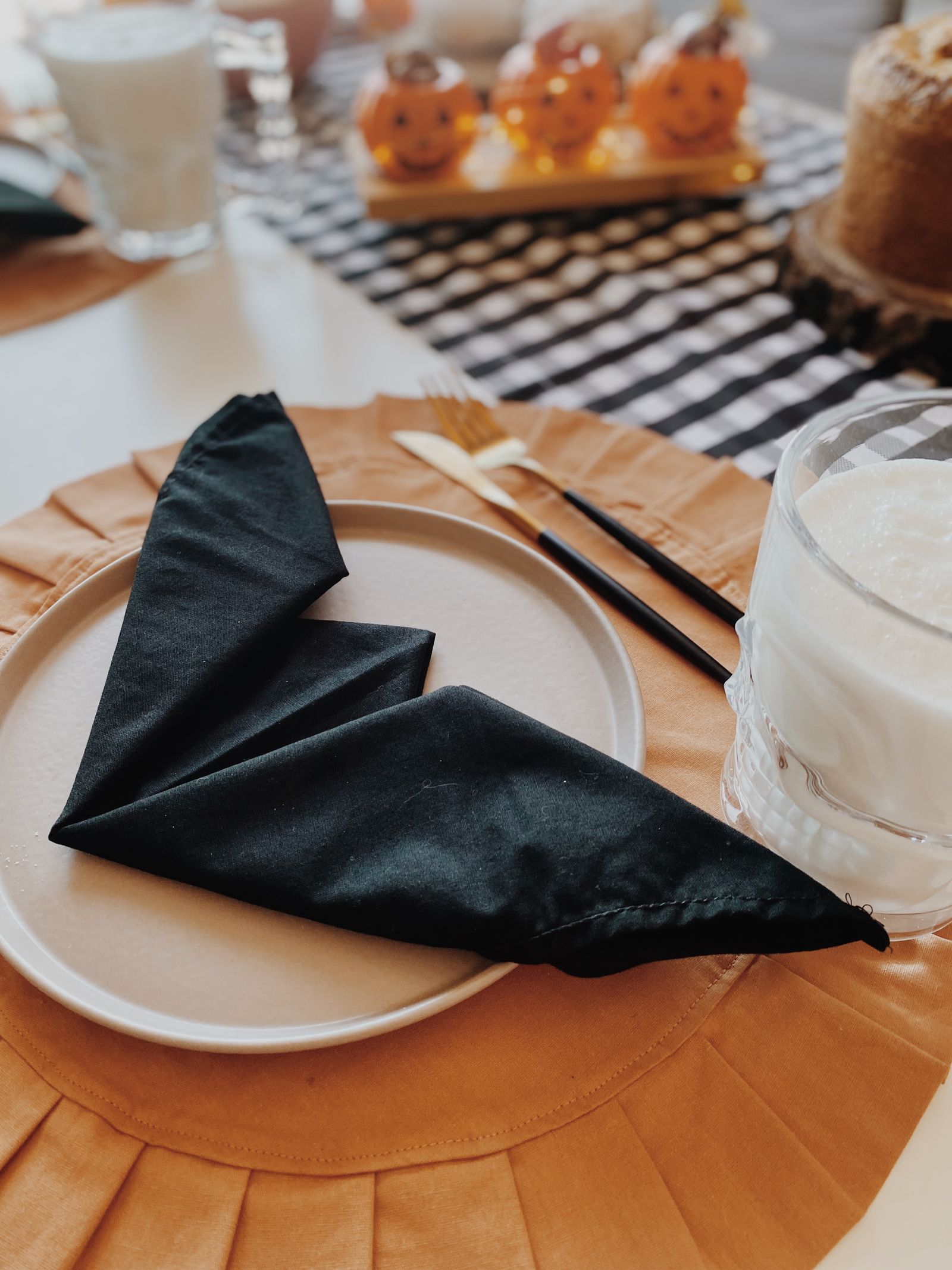 Halloween place setting with black napkins and pumpkin decorations