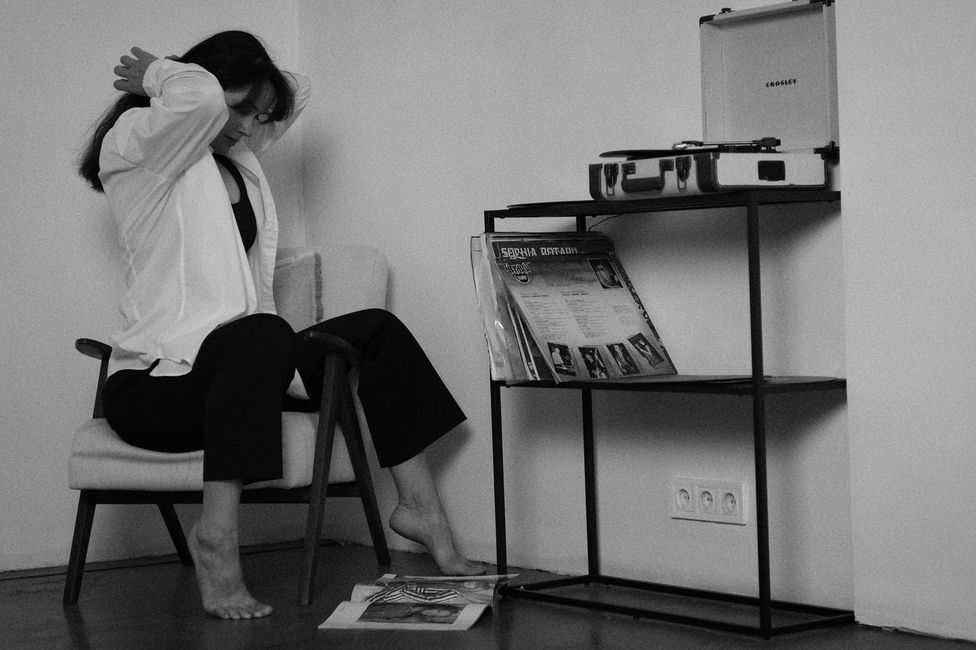A person listening with headphones beside a shelf-mounted record player