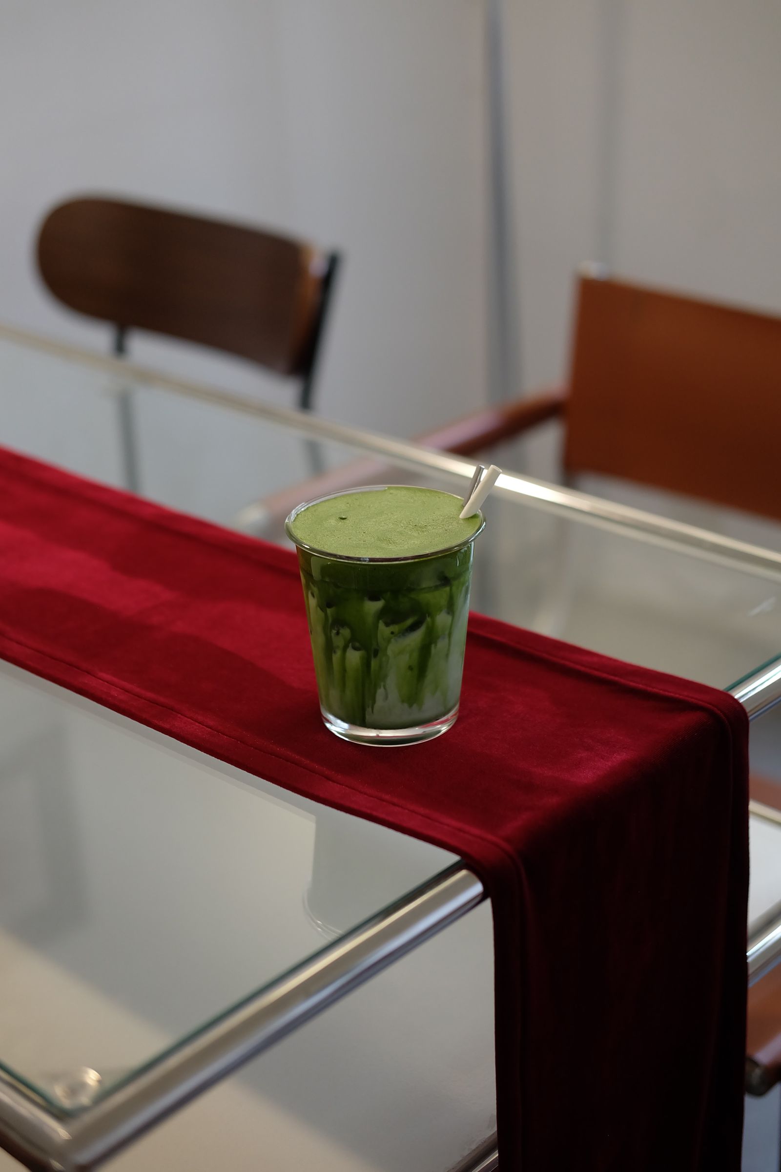 A red runner on a glass table beside dining chairs